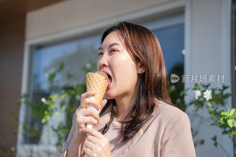 穿着便服的不健康亚洲年轻女子在咖啡馆外吃冰淇淋时牙痛，需要牙医检查。