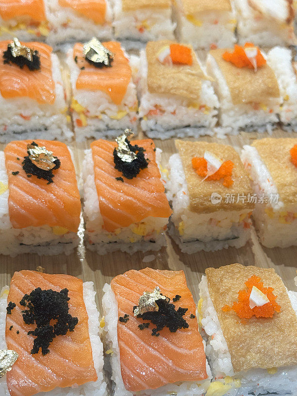 全画幅的寿司店展示了木板上一排排的寿司，鲑鱼(清酒)和油炸豆腐配以鱼子(tobiko)，高架视图