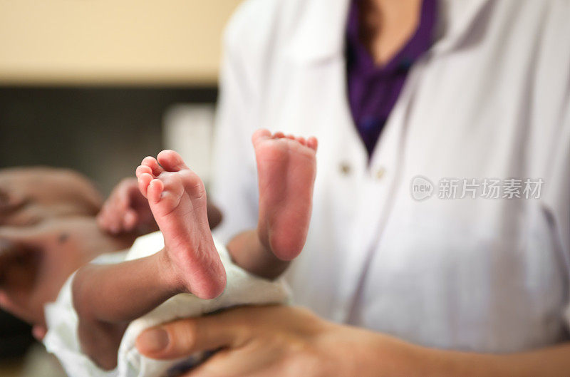 医生抱着小婴儿，双脚清晰可见。