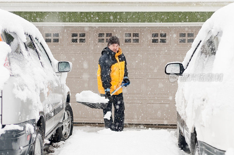 一名男子在暴风雪期间在车道上铲雪