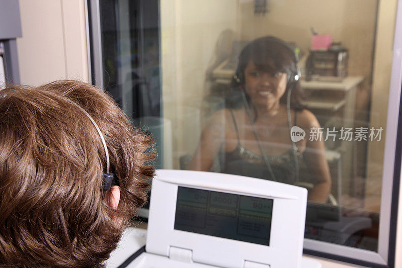 年轻女子在玻璃隔间完成听力测试