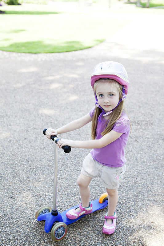小女孩骑着滑板车戴着安全帽