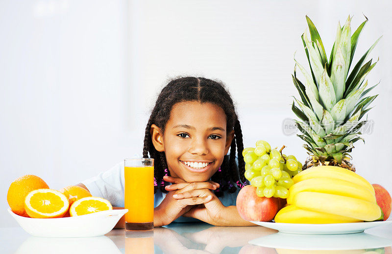 小女孩喝着橙汁和水果。