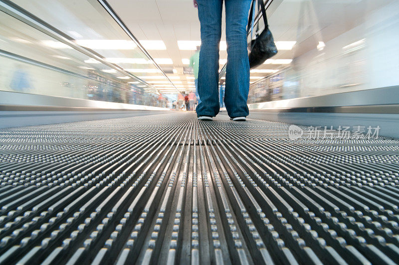 一个面目全非的女人站在机场的自动扶梯上
