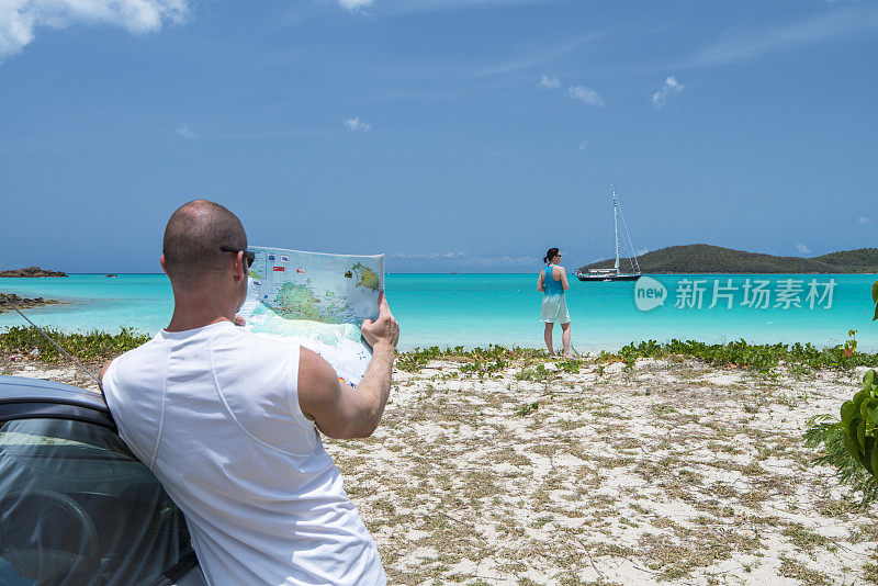 男人在车旁看地图，海滩