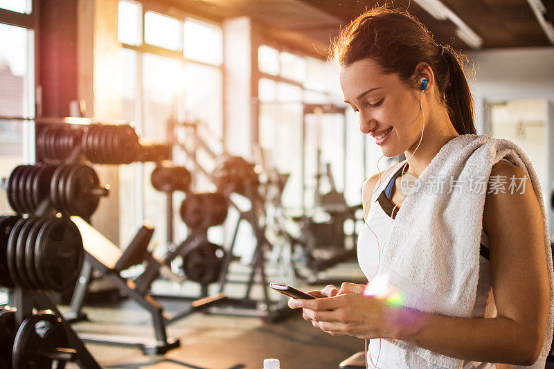活跃的女孩在健身房里使用智能手机。