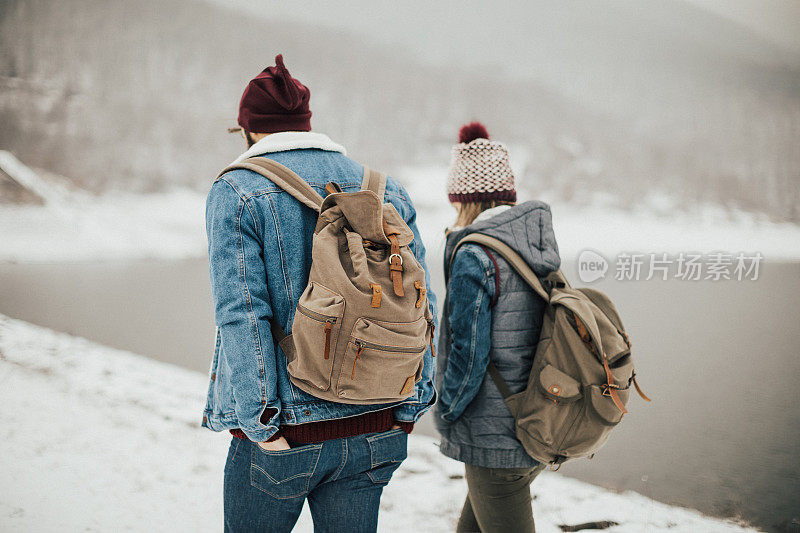 两个人在雪地上走。从后面看