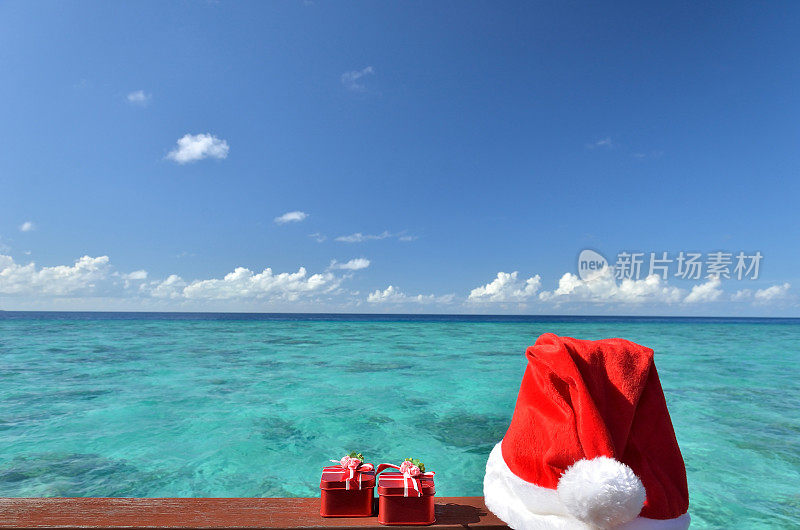 圣诞老人的红帽子和礼物旁边的热带绿色泻湖