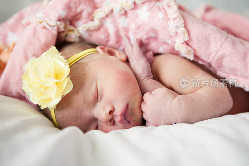 戴着黄花发带熟睡的新生女婴