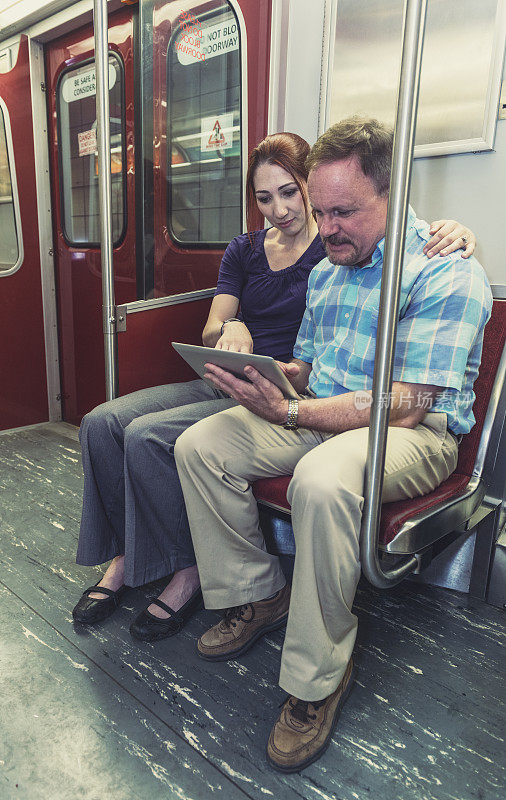 一对夫妇在地铁上带着平板电脑