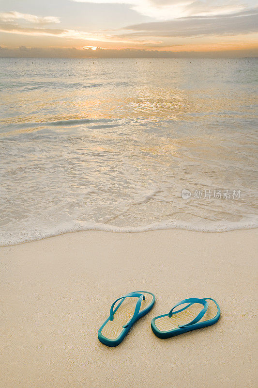 沙滩上的凉鞋在平稳的日出