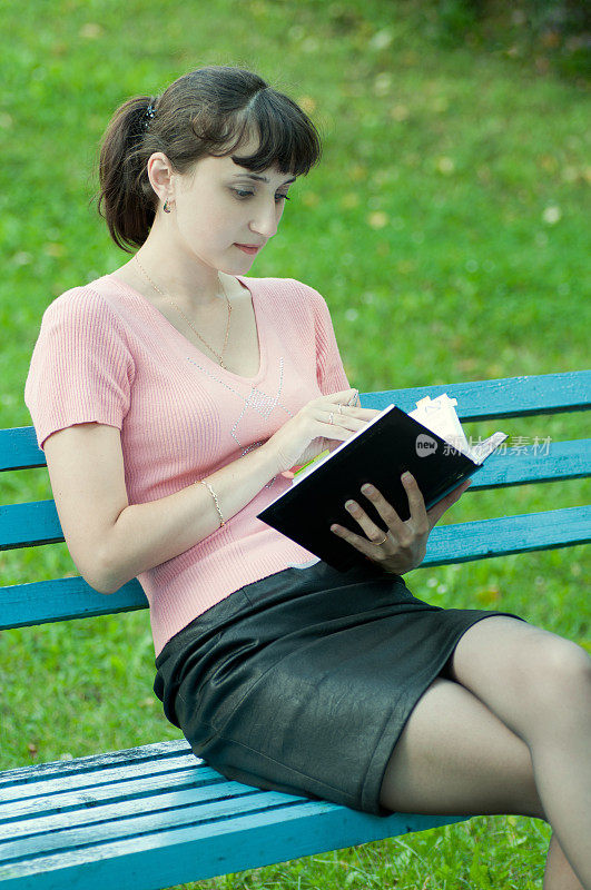 在公园里拿着笔记本的年轻女子