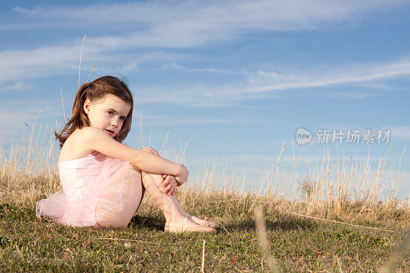 坐在户外大自然中的芭蕾舞小女孩