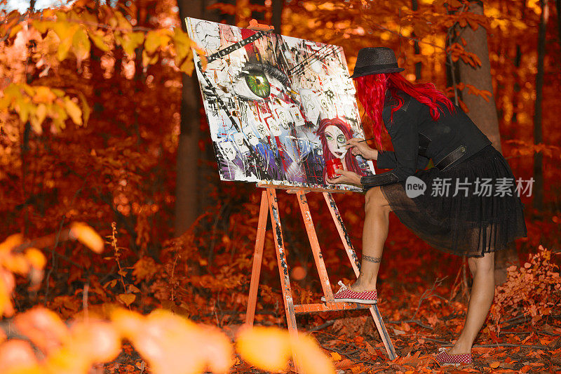 在森林里作画的红头发女人