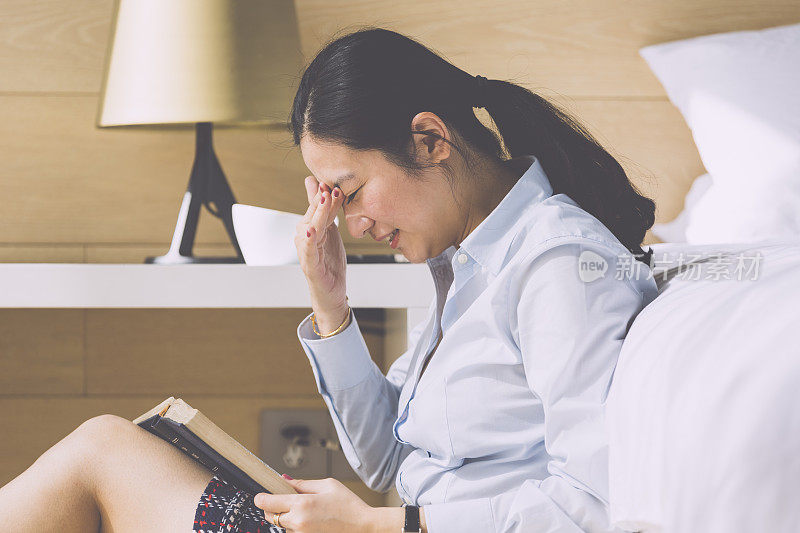 亚洲女商人在酒店房间里看书