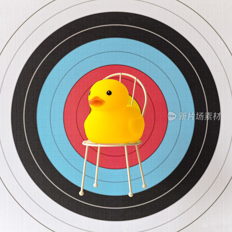 坐在椅子上的黄色橡皮鸭坐在一个体育目标的靶心前。