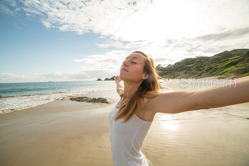 年轻女子在沙滩上张开双臂想要积极的情绪