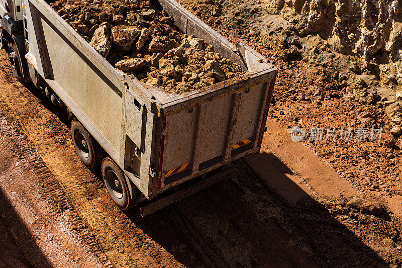 装满碎石的自卸卡车离开挖掘区域
