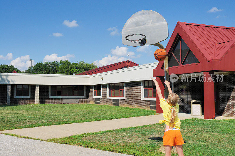 年轻的女孩在学校操场上打篮球