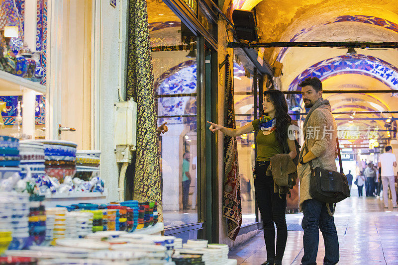 一对年轻的游客夫妇在土耳其伊斯坦布尔的大巴扎购买地毯