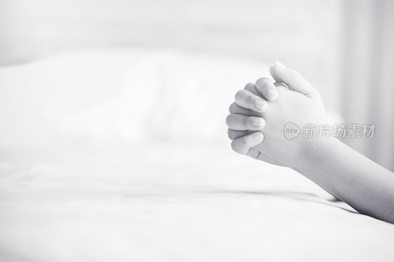 早上在床上祈祷的女人。少女女子手祈祷，双手合十祈祷在床上在早上的信念，精神和宗教的概念。黑色和白色。
