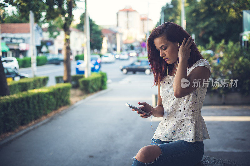 优雅的年轻女子在城里听她的音乐