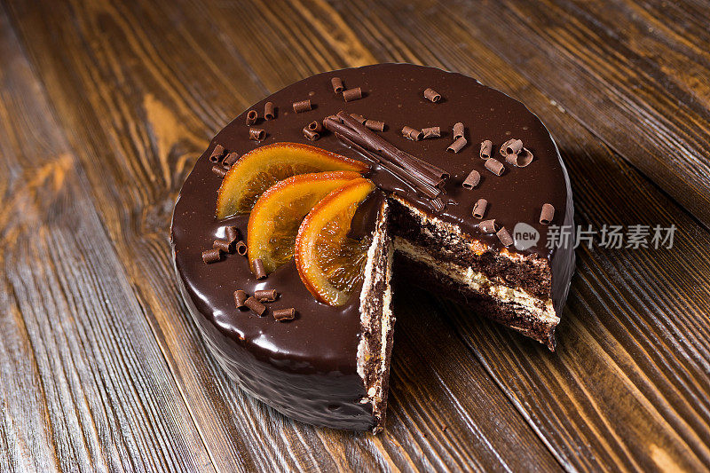 巧克力蛋糕与蜜饯橘子，巧克力蛋糕与切块和刀片在黑暗的背景，特写，黑巧克力蛋糕，美味的素食巧克力蛋糕，美味的巧克力蛋糕在木制的背景