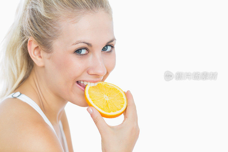 快乐的女人咬着一片橙子