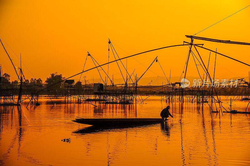 剪影渔民渔船捕鱼，使用传统的渔网工具在沼泽