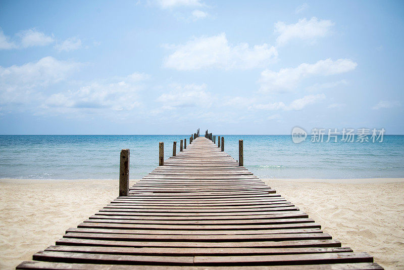 从海滩通向大海的粗糙的木制码头。