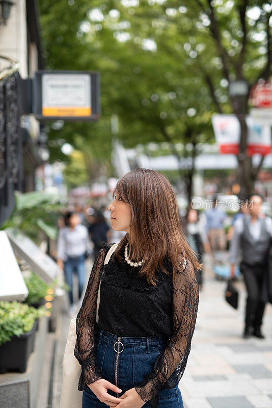 一名女子走在表参道大街上，这是日本最著名的街道之一