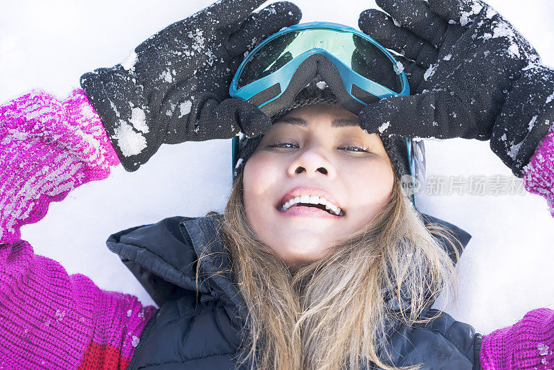 女滑雪板滑雪镜躺在雪地上的肖像