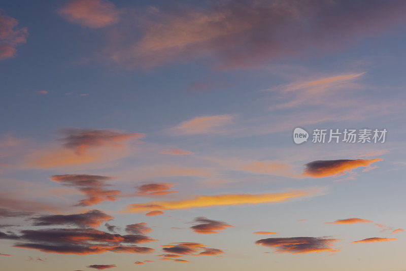 在蓝色的天空中，高积云和卷积云反射着日落的橘色光芒。