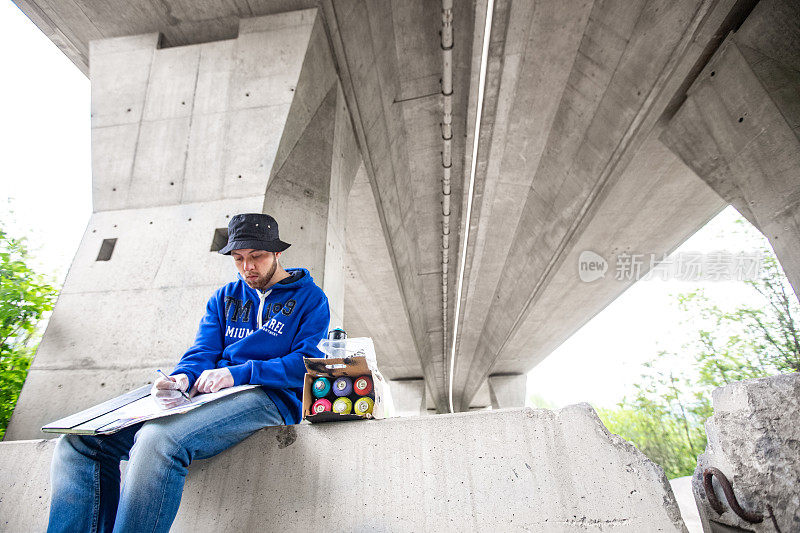 年轻的涂鸦艺术家在高速公路地下通道创作一个涂鸦之前做一个素描
