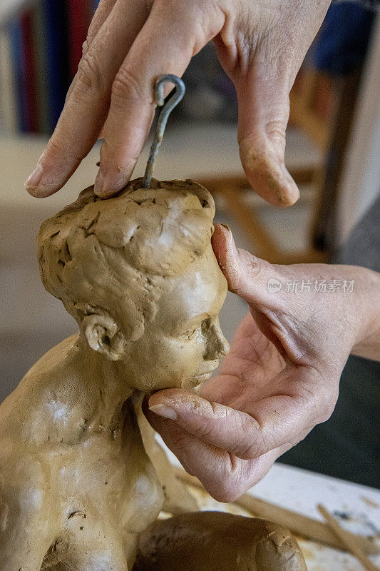 成熟的女性雕塑家在她的工作室里制作她的泥塑。