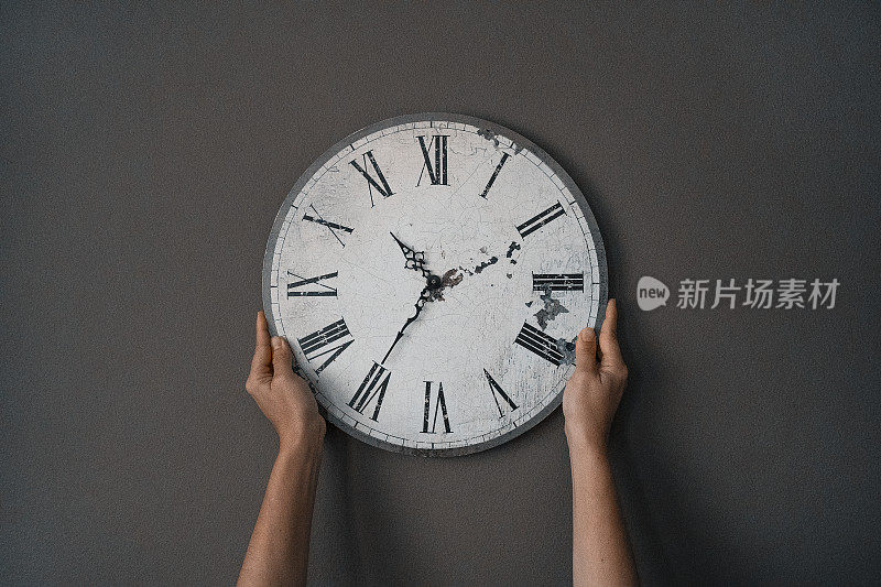 时间正在运行。抱着一个挂钟在深灰色的墙壁背景，工作钟，时间，拷贝空间-库存照片