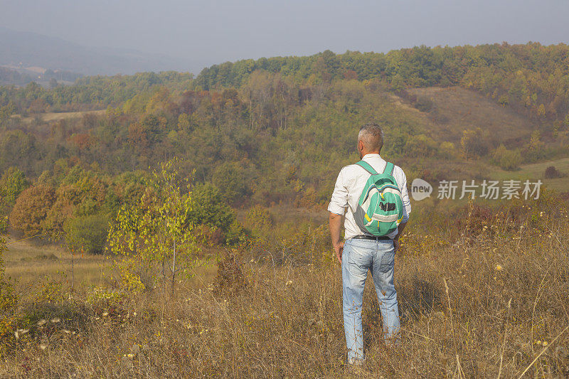 一名成年男子在阳光明媚的印度夏秋日徒步旅行在美丽的大自然中。