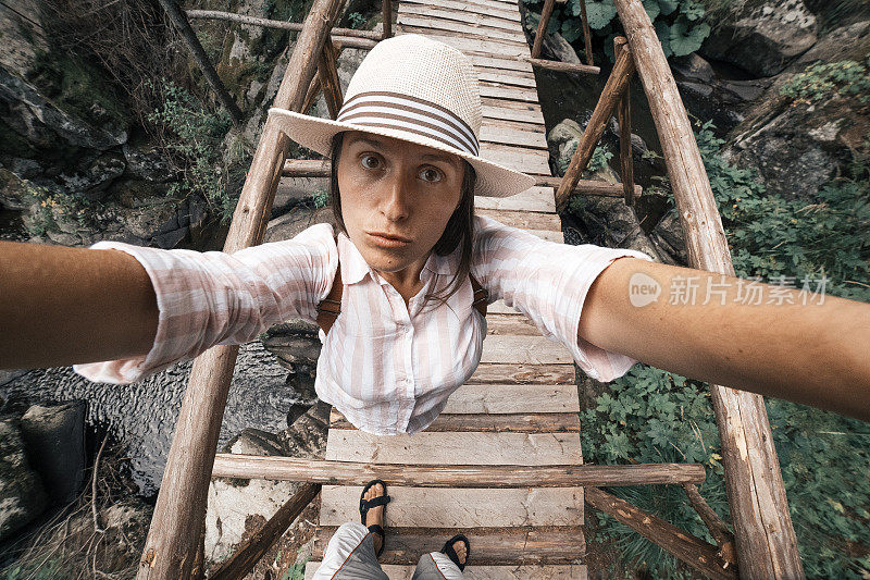 回归自然自拍。随心。一位快乐的年轻女游客在大自然中漫步，发现了一座古老的木桥。阳光明媚的户外享受。