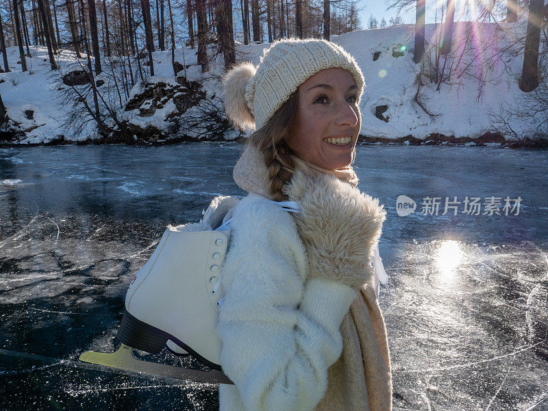 一个年轻女子肩上扛着冰鞋走在结冰的湖面上