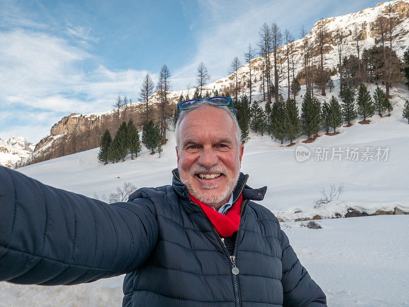 成熟的男人在冬天与雪山景自拍;人们在寒假里玩得很开心