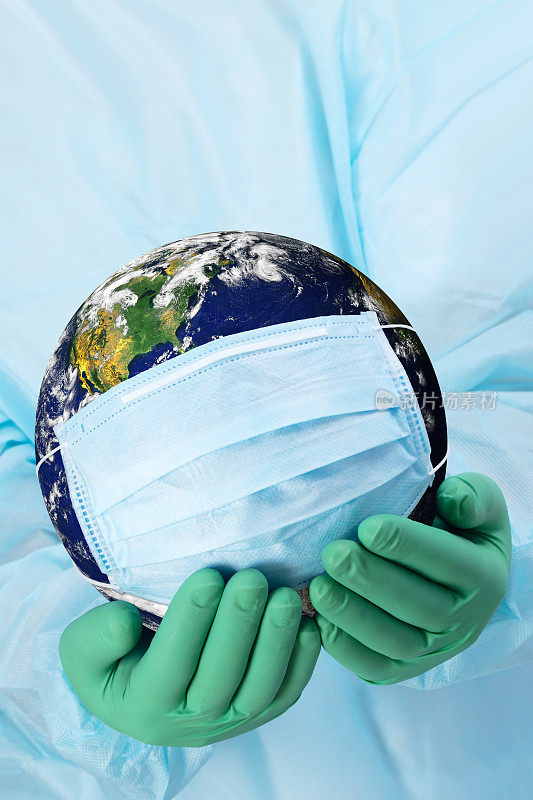 大流行概念-医生的手在手套拿着地球在一个医疗口罩