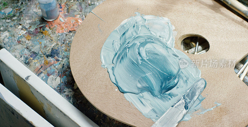 一个艺术家使用油漆刀在调色板上混合油漆的特写镜头