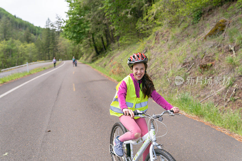 一个十几岁的小女孩在森林地区的乡间小路上骑着自行车