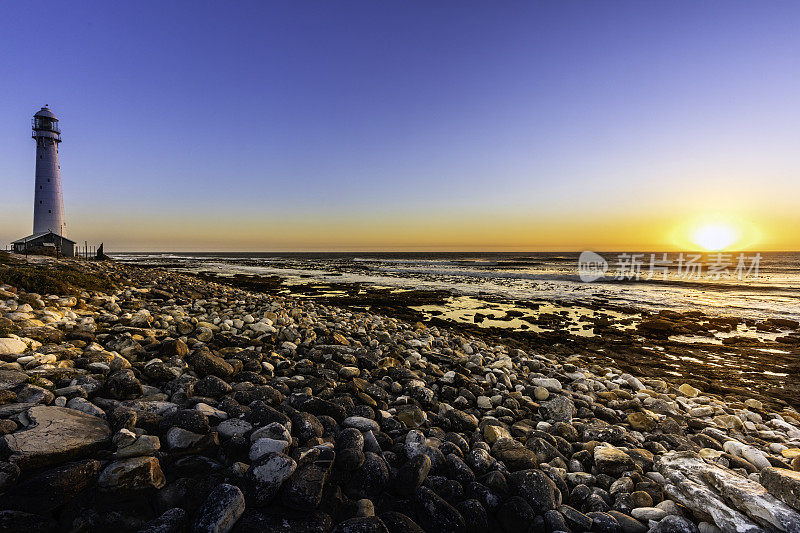 日落鹅卵石海滩的Slangkop灯塔