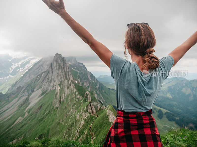 山顶上的女人张开双臂拥抱自由和自然