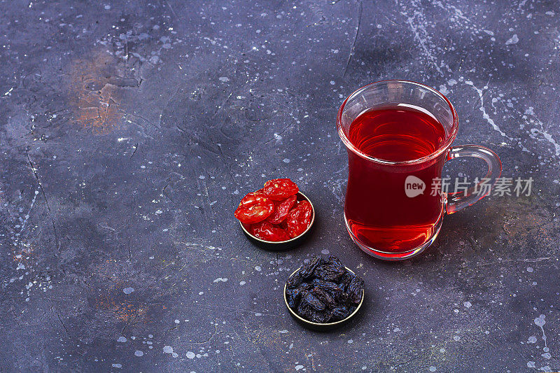 土耳其茶杯(armudu)红茶(roibos，木槿，karkade)和干果(山茱萸)在深色的背景上。草药，维生素，治疗感冒和流感的排毒茶。关闭，为文本复制空间