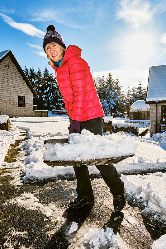 老妇人正在用雪铲清理前院的积雪