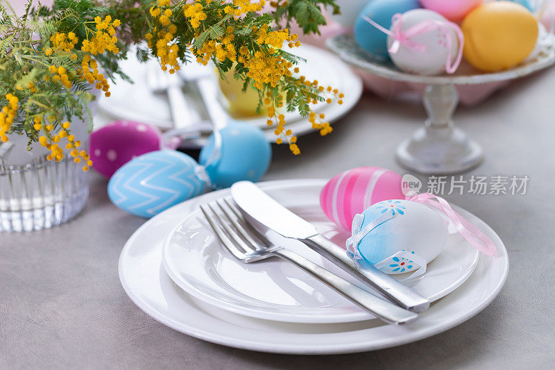 复活节餐桌上摆放含羞草花和餐具。节日的背景
