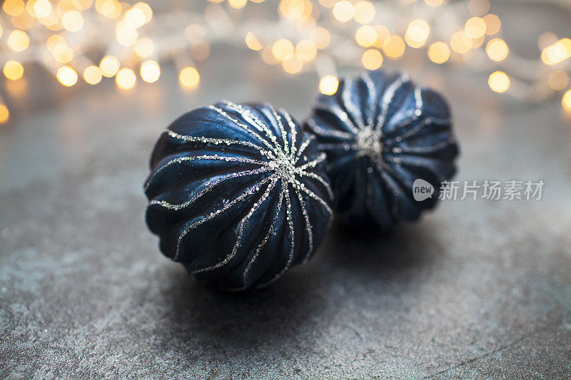 黑色的表面上挂着蓝色的圣诞装饰物，还有模糊的串灯