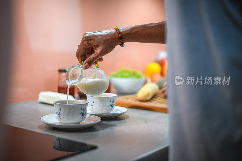 一名西班牙妇女在早上往咖啡里倒牛奶
